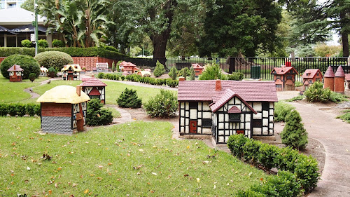 Image of a small model town in a city garden. The small buildings are mostly an off-white and dark red.