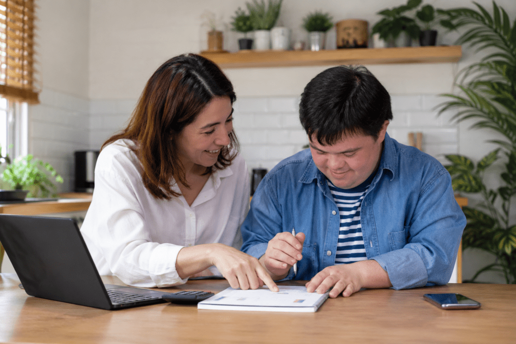 Support worker helping a person with intellectual disability review financial information and make supported decisions at home.